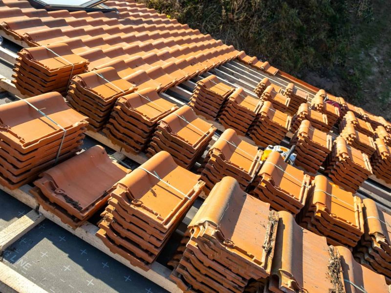 Stacks of clay roof tiles arranged on a residential roof during installation.